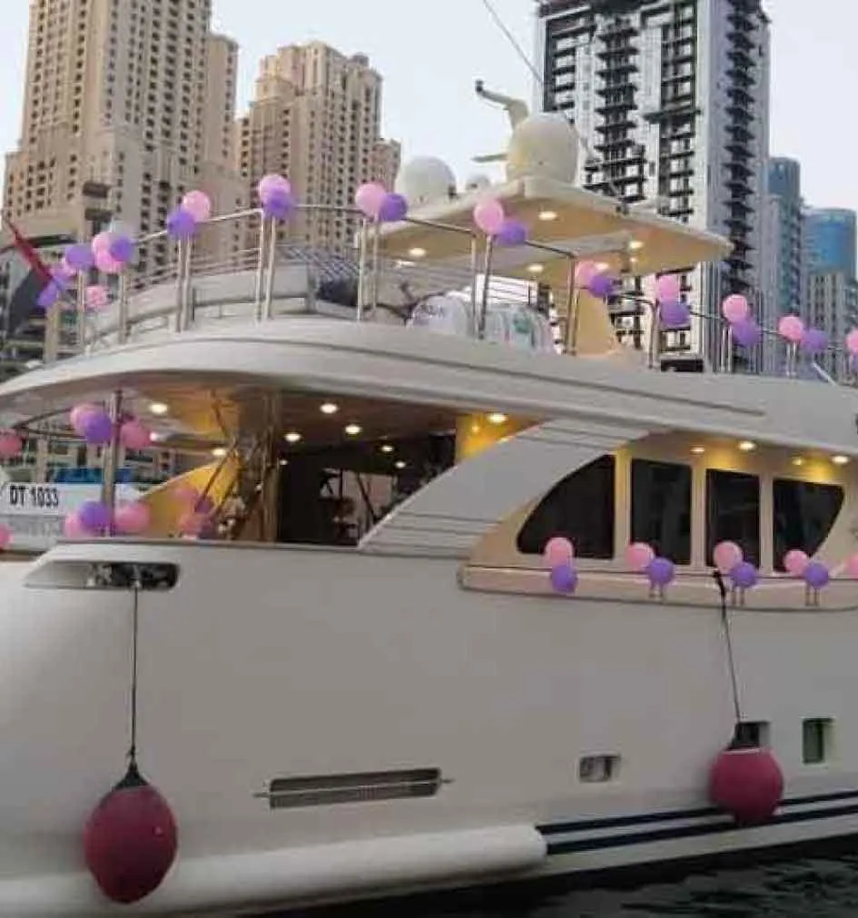 A large yacht adorned with pink balloons for a birthday party in Dubai.